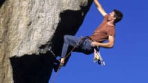 man climbing a steep faced rock