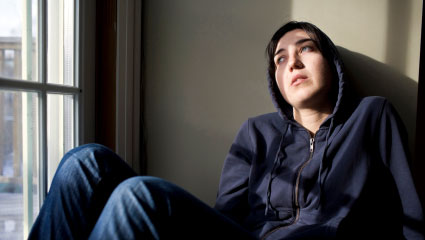 woman looking out of a window with a depressed expression on her face
