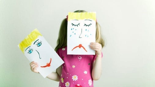 girl with a paper with a sad face in front of her face