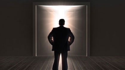 man backlit by a doorway opening with light