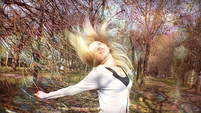 woman flicking her hair in the sunlight in the forest