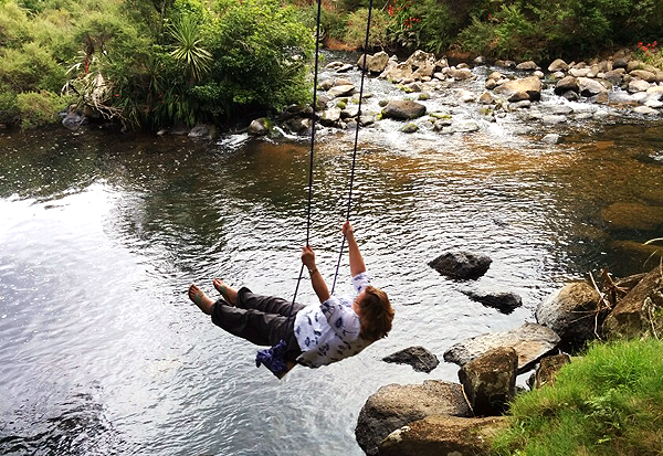 woman on a swing over a stream