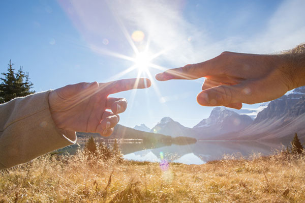 Two fingers touching with the sun between them