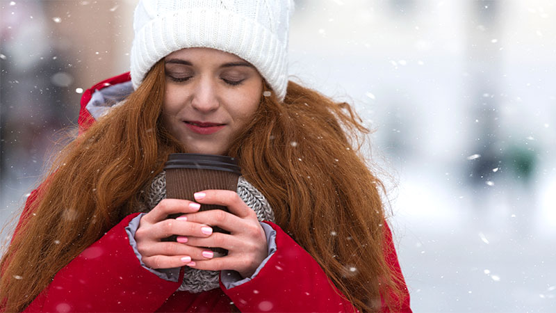 Girl in the snow holding hot coffee