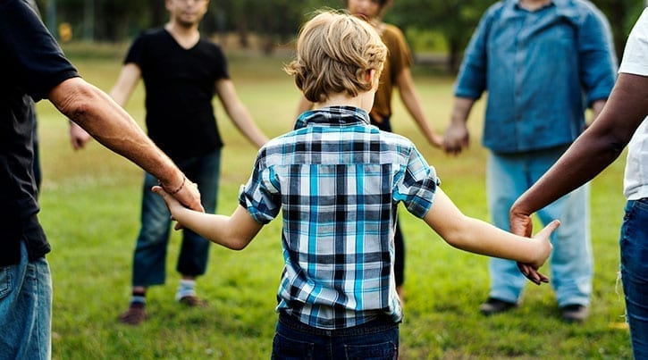 Mixed group of people holding hands in a field.