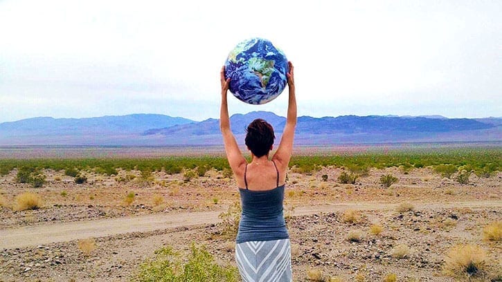 woman holding a globe over her head in the desert