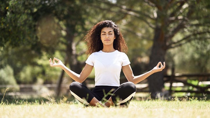 Young Arab woman meditating on grass