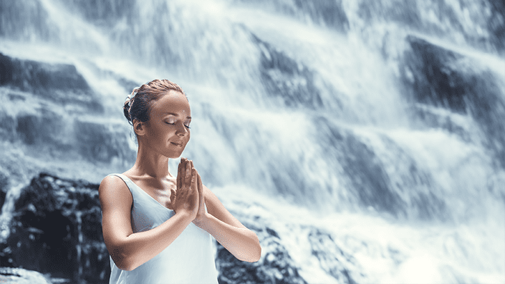 woman meditating at a waterfall