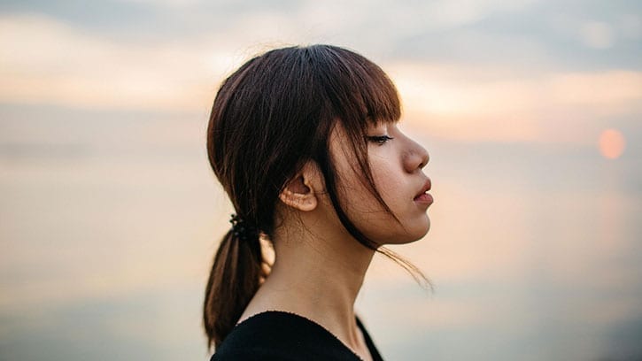 young woman closing her eyes to the setting sun