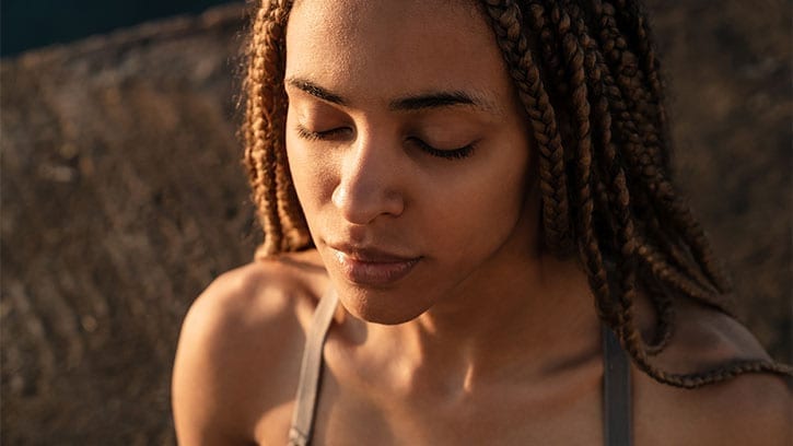 close-up of young woman meditating on a beach