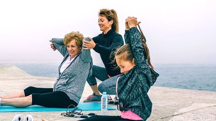 grandmother, mother, and daughter, 3 generations stretching on beach