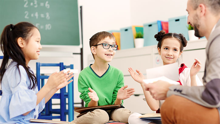 kids clapping their hands for their teacher in school