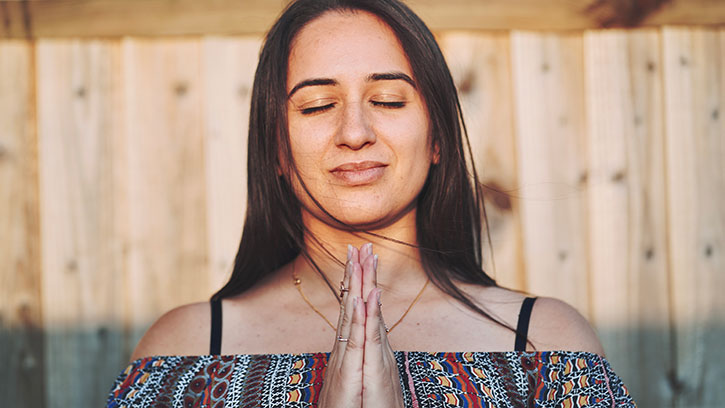 young woman meditating outside in soft sunlight