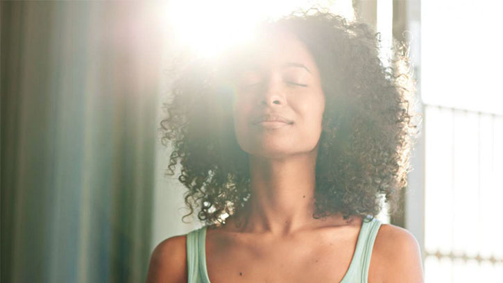 woman meditating with sunlight behind her head