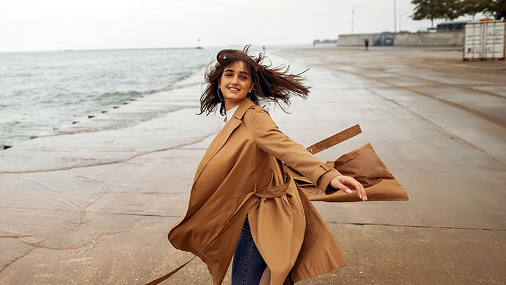 woman twirling at the beach in a trench coat
