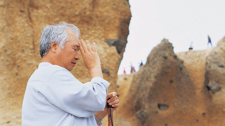 Ilchi Lee praying in among the rocks