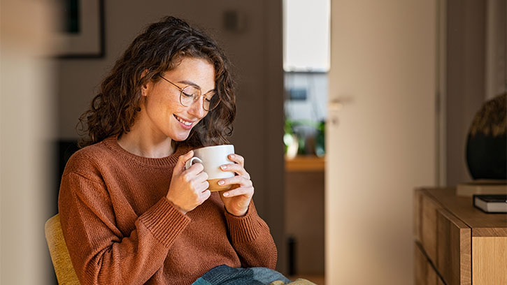 young woman in a sweater drinking a hot drink