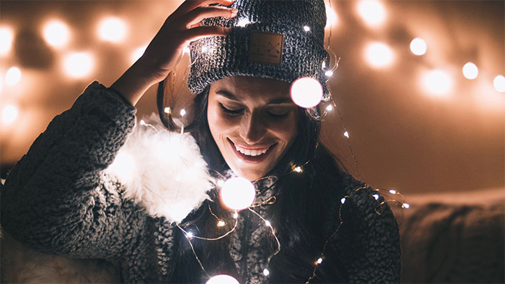 young woman outside among Christmas lights in the winter darkness