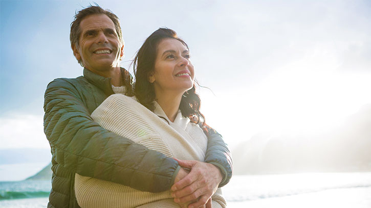 man backhugging woman in nature, blue sky