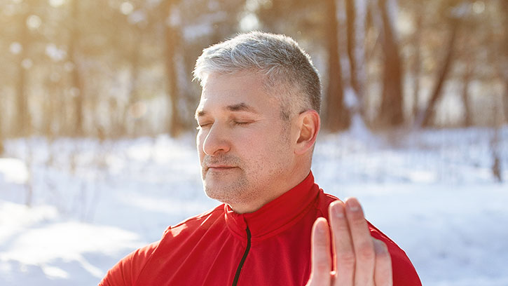 older man meditating in snow