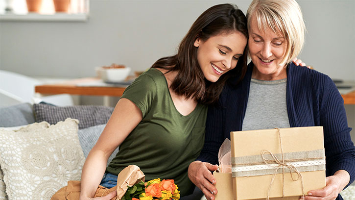 adult daughter giving mother a gift