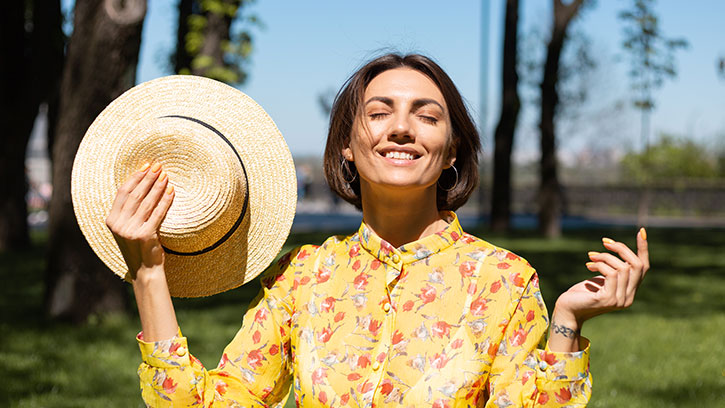 woman with hat smiling outside