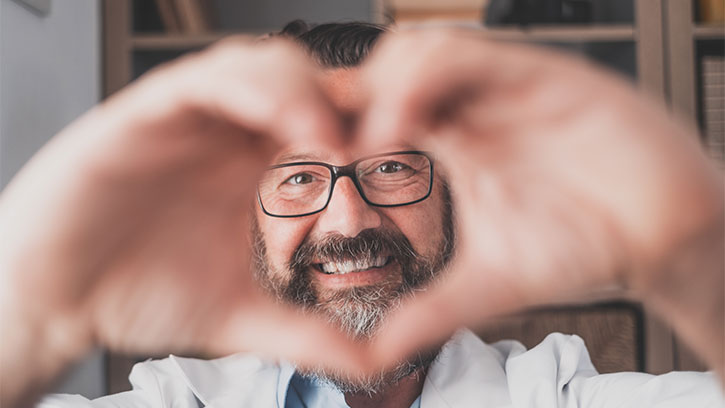 man with a beard holding his two hands made into a heart sign in front of his face