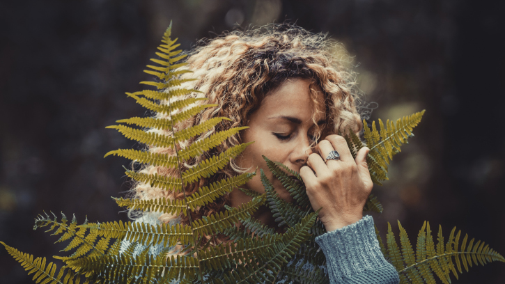 People and nature love concept lifestyle. Woman embracing big plant leaf in the woods with care and protection. Environment and outdoors climate change warming concept