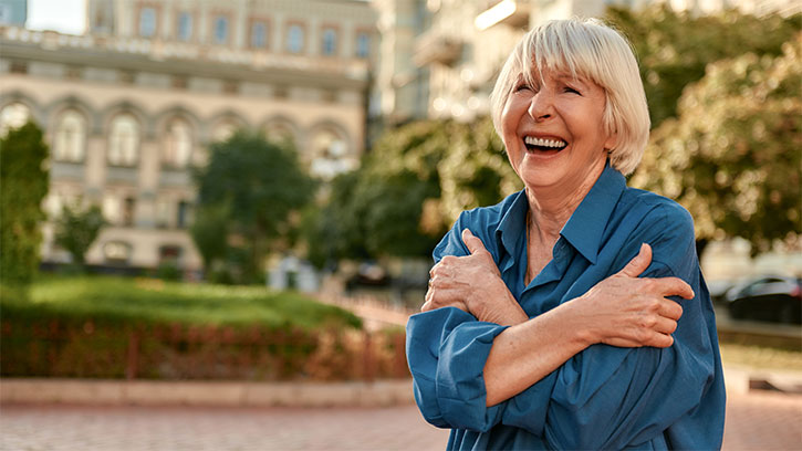 Older woman outside hugging herself