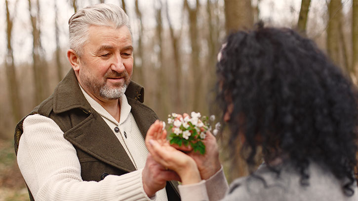 woman giving an older man a flowering plant
