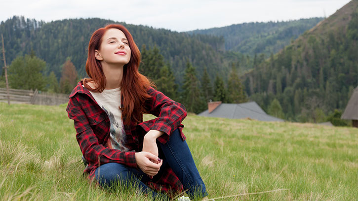 young woman enjoying nature sitting on grass