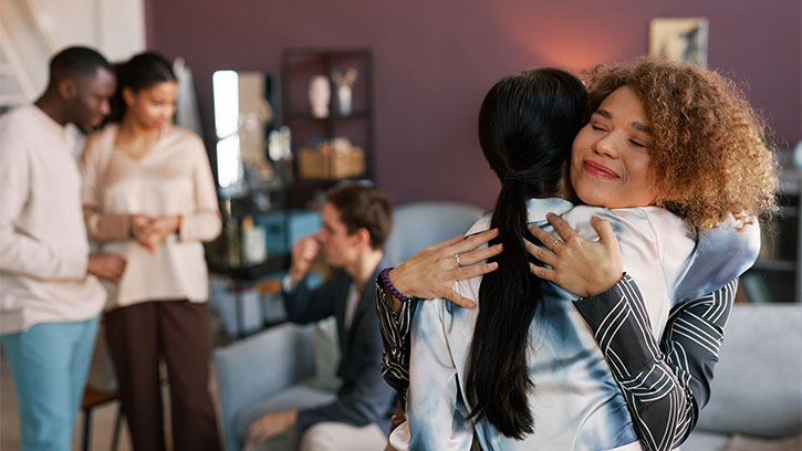 Two women greeting each other with a hug at a house party