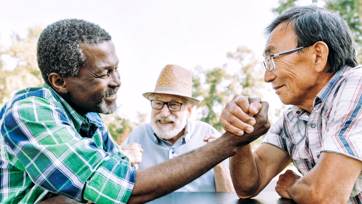 older men arm wrestling in a park