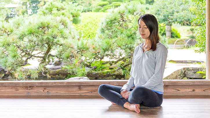 Asian woman sitting half lotus outside