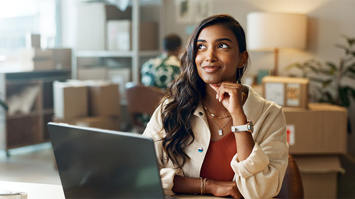 young woman with long dark hair in front of a laptop in a warehouse office