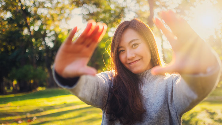 young Asian woman outside with palms forward