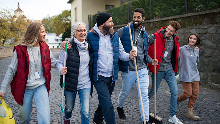mixed group of adults holding cleaning tools