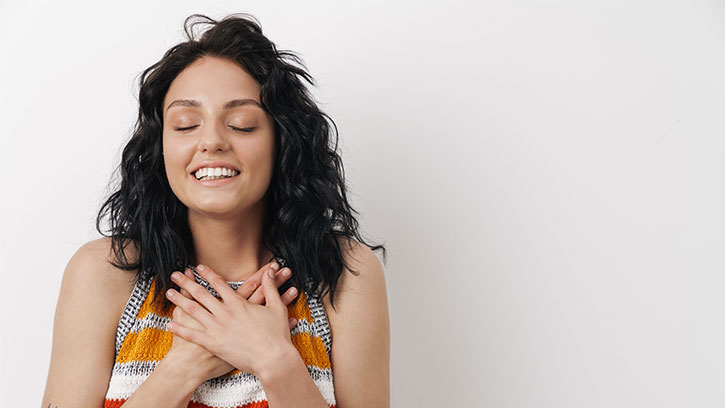 young woman smiling with hands over heart