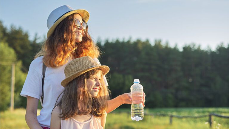 mother and child looking out into a field with child holding a water bottle