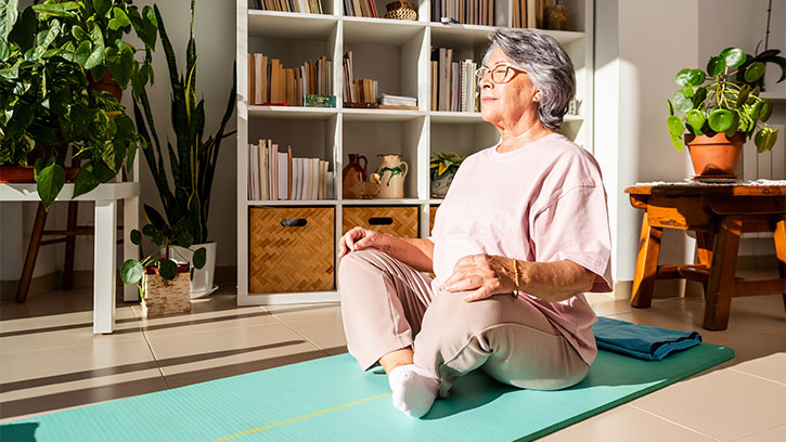 Senior Woman Meditating at Home on Yoga Mat