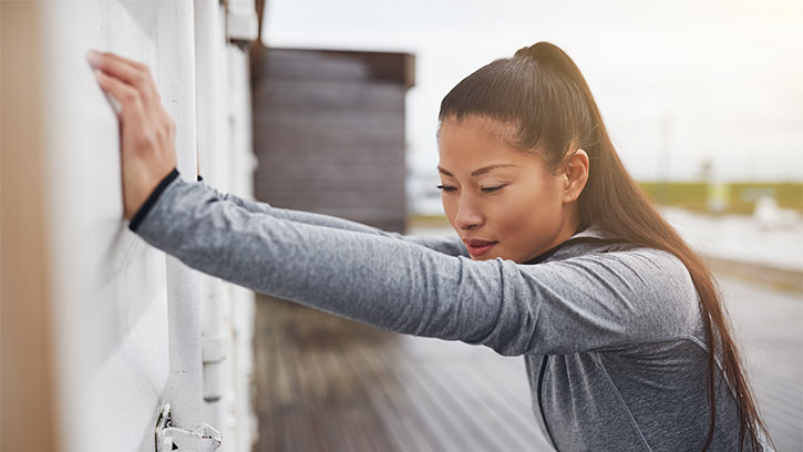 woman exercising while leaning her hands against the wall
