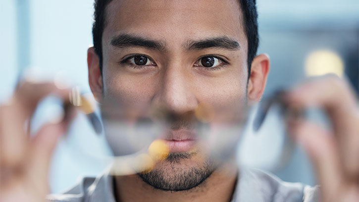 close up of man looking through blurred, rimless glasses