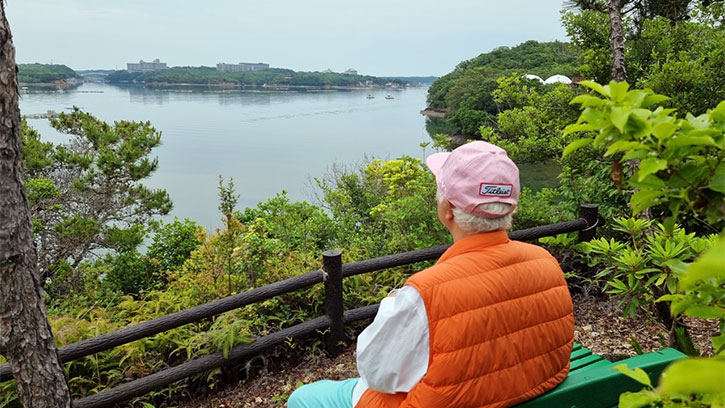 Ilchi Lee sitting on a bench overlooking a lake