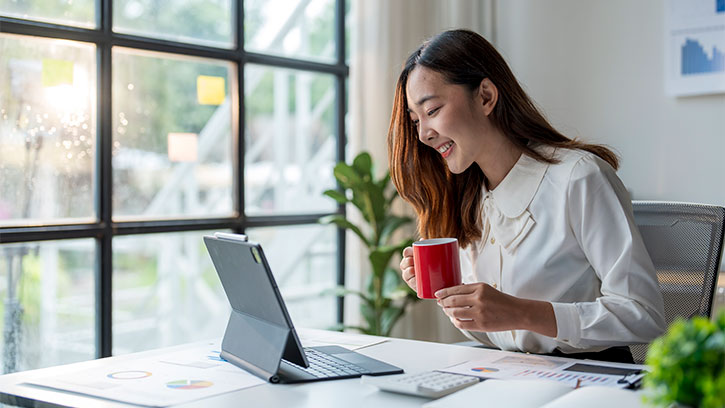 Smiling Woman Enjoying Coffee While Working